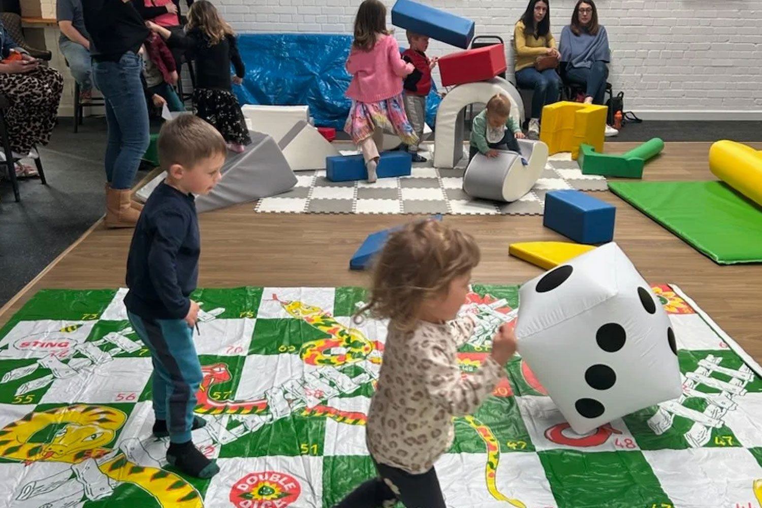 Toddlers and children playing on softplay mats and equipment.