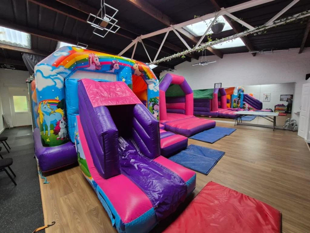 Colourful unicorn bouncy castle set up inside a children’s party hall