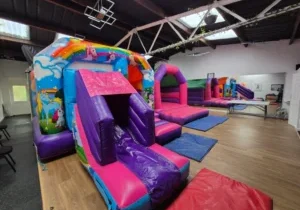Colourful unicorn bouncy castle set up inside a children’s party hall